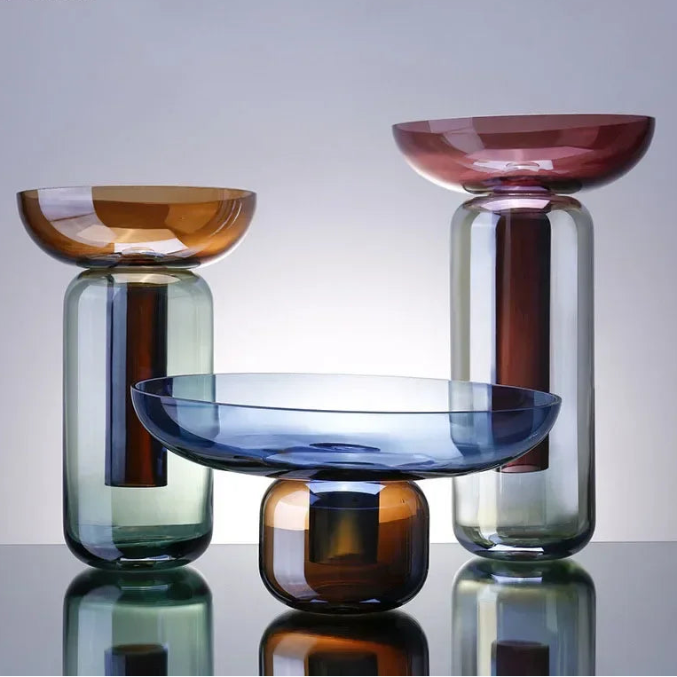 Set of colorful glass bowls on a reflective surface with a neutral background