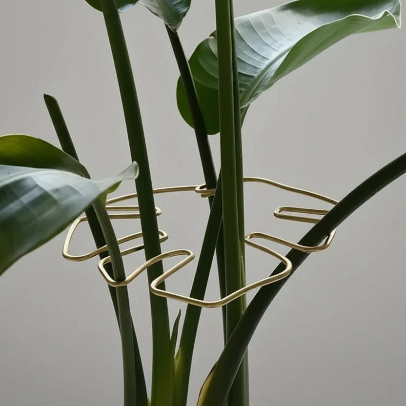 Gold plant support structure on a green plant with a blurred indoor background