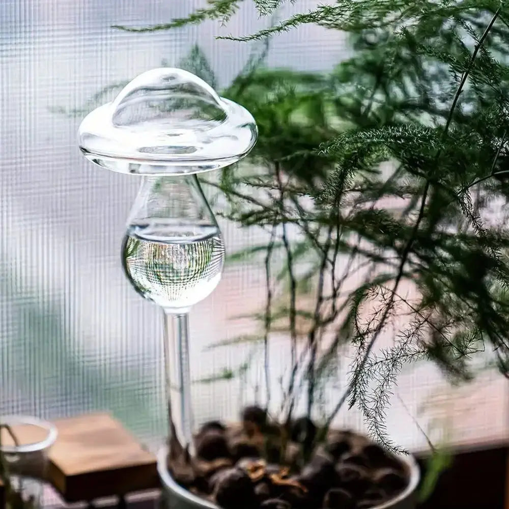 Glass water droplet sculpture with plants in the background