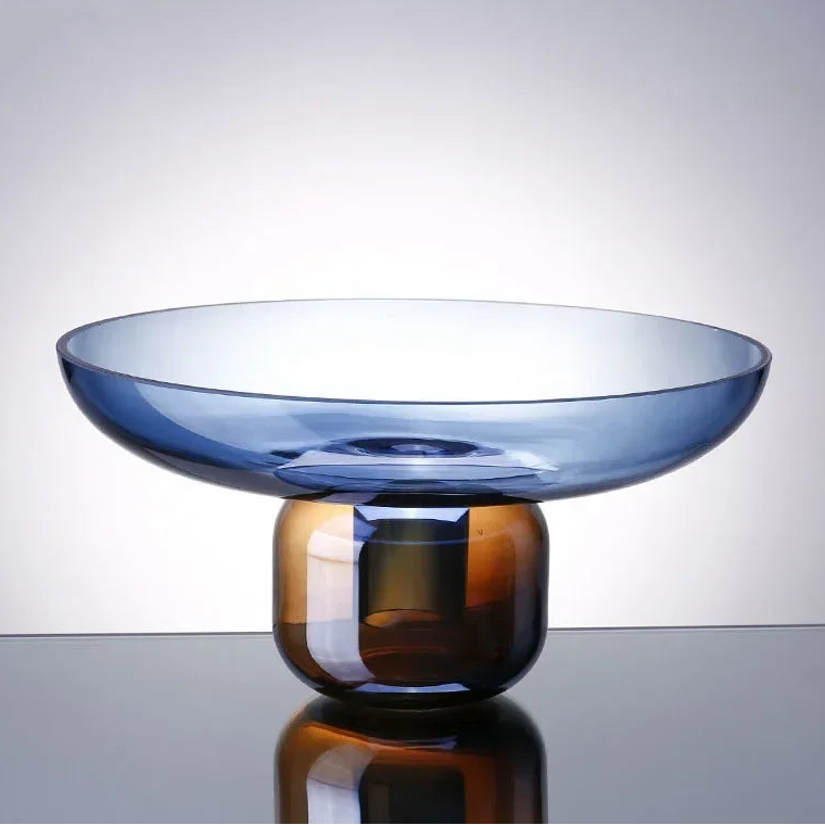 Two-toned glass bowl with blue and amber colors on a reflective surface.