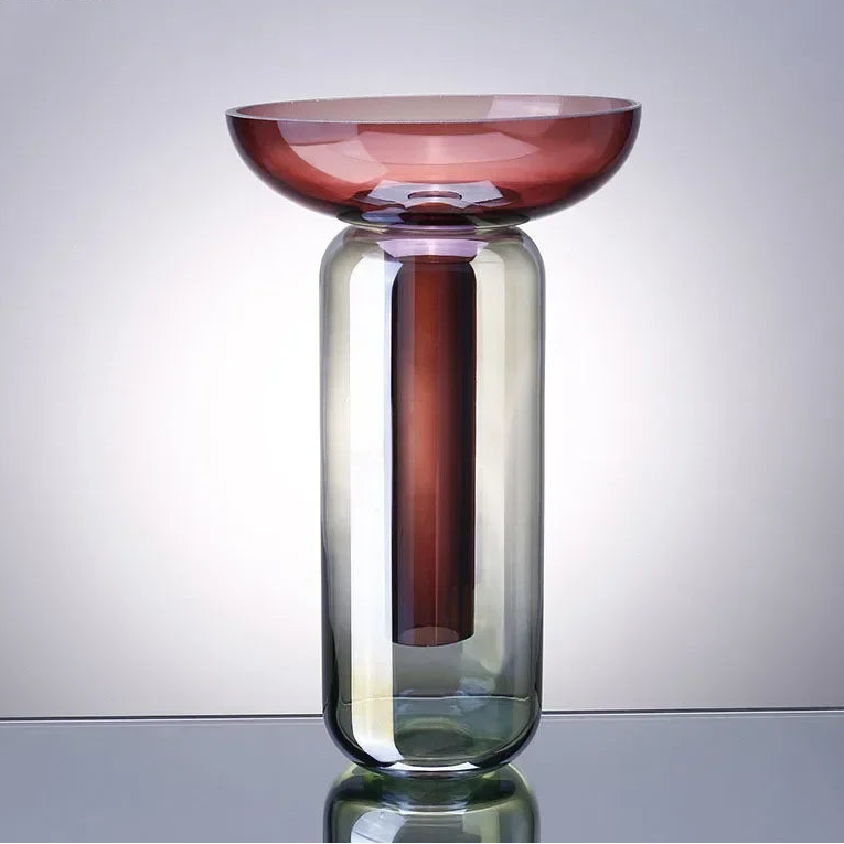 Glass vase with gradient color design on a reflective surface